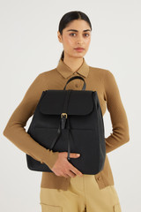Profile view of model wearing the Oroton Dylan Large Zip Buckle Backpack in Black and Pebble Leather for Women