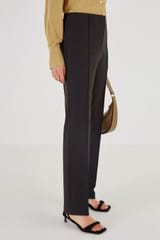 Profile view of model wearing the Oroton Technical Stretch Pant in Black and 51% Cotton 36% Polyester 13% Elastane for Women