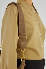 Profile view of model wearing the Oroton Logo Webbing Bag Strap in Willow and Smooth Leather for Women