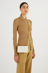 Profile view of model wearing the Oroton Fay Mini Chain Crossbody in Rich Cream and Nappa Leather for Women