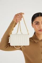 Profile view of model wearing the Oroton Fay Mini Chain Crossbody in Rich Cream and Nappa Leather for Women