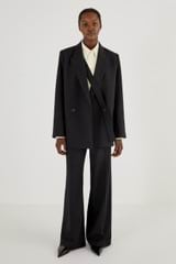 Profile view of model wearing the Oroton Flat Front Pant in Black and 53% Polyester 42% Wool 5% Elastane for Women
