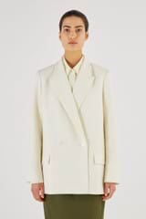 Profile view of model wearing the Oroton Double Breasted Blazer in Cream and 53% Polyester 43% Wool 4% Elastane for Women