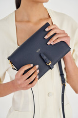Profile view of model wearing the Oroton Dylan Fold Over Crossbody in Dark Navy and Pebble Leather for Women