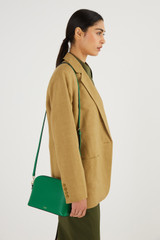 Profile view of model wearing the Oroton Inez Slim Crossbody in Emerald and Shiny Soft Saffiano for Women