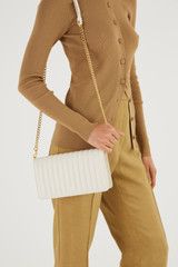 Profile view of model wearing the Oroton Fay Medium Chain Crossbody in Rich Cream and Nappa Leather for Women