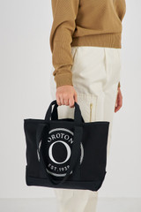 Profile view of model wearing the Oroton Kane Small Shopper Tote in Black and Recycled Canvas for Women