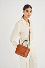 Profile view of model wearing the Oroton Harvey Small Tote in Cognac and Smooth leather for Women