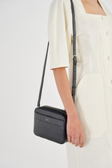 Profile view of model wearing the Oroton Harvey Camera Crossbody in Black and Smooth Leather for Women