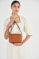 Profile view of model wearing the Oroton Harvey Camera Crossbody in Cognac and Smooth Leather for Women