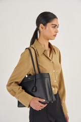 Profile view of model wearing the Oroton Harvey Medium Tote in Black and Smooth Leather for Women