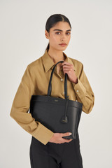 Profile view of model wearing the Oroton Harvey Medium Tote in Black and Smooth Leather for Women
