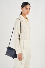 Profile view of model wearing the Oroton Sadie Crossbody in Dark Navy and Pebble Leather for Women