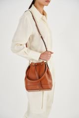 Profile view of model wearing the Oroton Harvey Bucket in Cognac and Smooth leather for Women