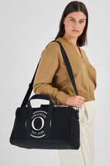Profile view of model wearing the Oroton Kane Carry All in Black and Recycled Canvas for Women