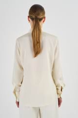 Profile view of model wearing the Oroton Slim Fit Silk Shirt in Vanilla Bean and 93% Silk 7% Spandex for Women