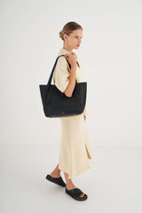 Profile view of model wearing the Oroton Dylan Medium Tote in Black and Pebble Leather for Women