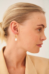 Profile view of model wearing the Oroton Violet Pearl Huggies in Gold/White and Brass Base With 18CT Gold Plating for Women