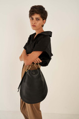 Profile view of model wearing the Oroton Lyla Hobo in Black and Pebble Leather for Women