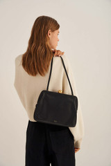 Profile view of model wearing the Oroton Nova Day Bag in Black and Smooth Leather for Women