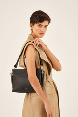 Profile view of model wearing the Oroton Lyla Day Bag in Black and Pebble Leather/Smooth Leather for Women