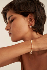 Profile view of model wearing the Oroton Olenna Bracelet in Gold/Pearl and Brass Base With 18CT Gold Plating for Women