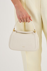 Profile view of model wearing the Oroton Reed Small Day Bag in Clotted Cream and Pebble Leather for Women