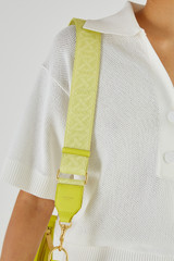 Profile view of model wearing the Oroton Logo Webbing Bag Strap in Bright Chartreuse and Smooth Leather for Women
