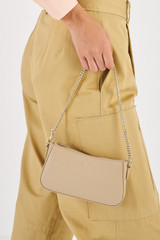 Profile view of model wearing the Oroton Inez Chain Wristlet in Fawn and Saffiano Leather for Women