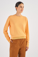 Profile view of model wearing the Oroton Long Sleeve Cashmere Crew Knit in Apricot and 100% Cashmere for Women
