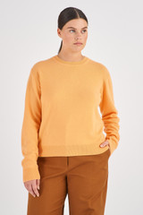 Profile view of model wearing the Oroton Long Sleeve Cashmere Crew Knit in Apricot and 100% Cashmere for Women
