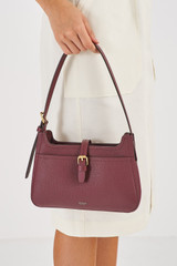 Profile view of model wearing the Oroton Dylan Baguette in Merlot and Pebble Leather for Women
