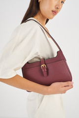 Profile view of model wearing the Oroton Dylan Baguette in Merlot and Pebble Leather for Women