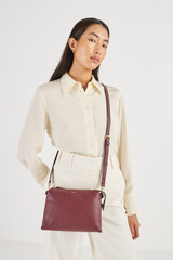 Profile view of model wearing the Oroton Sadie Crossbody in Merlot and  for Women