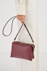 Profile view of model wearing the Oroton Sadie Crossbody in Merlot and Pebble Leather for Women