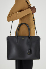 Profile view of model wearing the Oroton Muse 15" Worker Tote in Black and Saffiano leather for Women