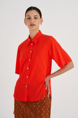 Profile view of model wearing the Oroton Short Sleeve Fluid Shirt in True Red and 92% Silk, 8% Spandex for Women