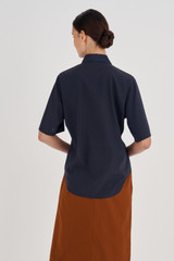Profile view of model wearing the Oroton Short Sleeve Fluid Shirt in North Sea and 92% Silk, 8% Spandex for Women