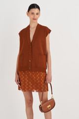 Profile view of model wearing the Oroton Sleeveless Knit Vest in Tan and 83% Viscose, 17% Polyester for Women