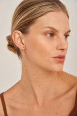 Profile view of model wearing the Oroton Petite Luna Letter Hoop Earrings in Gold and Brass Base With 18CT Gold Plating for Women