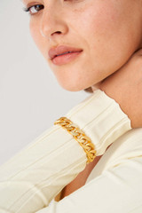 Profile view of model wearing the Oroton Noa Texture Bracelet in Worn Gold and Brass Base With 18CT Gold Plating for Women