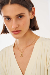 Profile view of model wearing the Oroton Gemma Alphabet Letter Necklace in Worn Gold and Brass Base With 18CT Gold Plating for Women