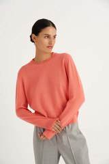 Profile view of model wearing the Oroton Long Sleeve Cashmere Crew Neck in Sherbet and 100% Cashmere for Women