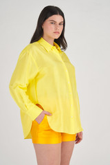 Profile view of model wearing the Oroton Silk Long Sleeve Shirt in Vibrant Yellow and 100% Silk for Women