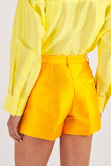 Profile view of model wearing the Oroton Tailored Short in Marigold and 86% Polyester, 14% Silk for Women