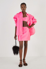 Profile view of model wearing the Oroton Satin Mini Skirt in Candy Pink and 85% Polyester, 15% Silk for Women