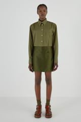 Profile view of model wearing the Oroton Satin Mini Skirt in Khaki and 85% Polyester, 15% Silk for Women