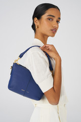 Profile view of model wearing the Oroton Lilly Zip Top Crossbody in Azure Blue and Pebble Leather for Women