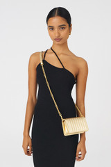 Profile view of model wearing the Oroton Fay Mini Chain Crossbody in Gold and Metallic Pebble Leather for Women