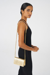 Profile view of model wearing the Oroton Fay Mini Chain Crossbody in Gold and Metallic Pebble Leather for Women